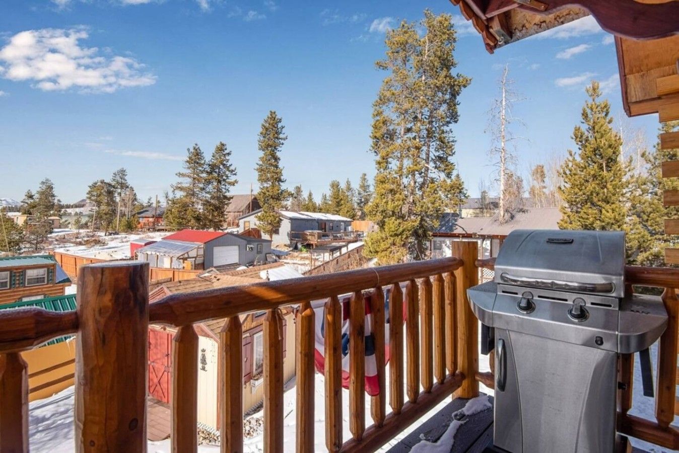 A balcony with a grill, overlooking a residential area with houses and trees.