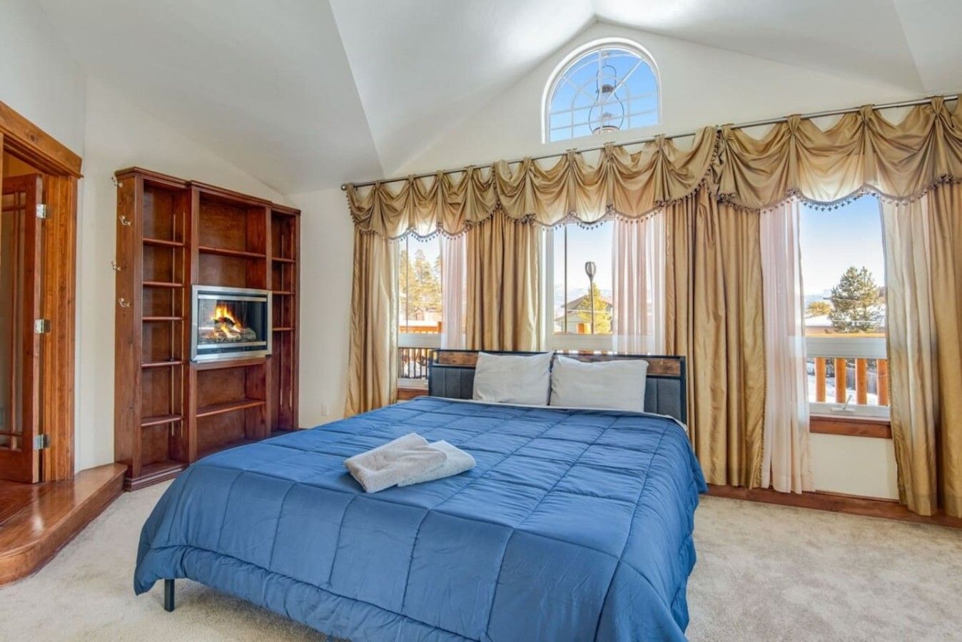 A bedroom with a large bed, a television, and a fireplace.