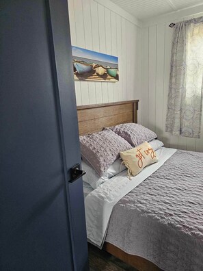 Un dormitorio con una cama, un cuadro en la pared y una puerta.