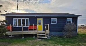 Einbungalow mit einer Veranda, einer gelben Tür und einer kleinen Terrasse.