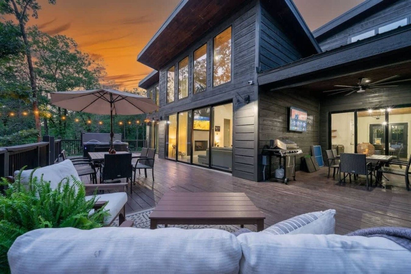 A modern outdoor deck with a dining area, seating, and a grill.