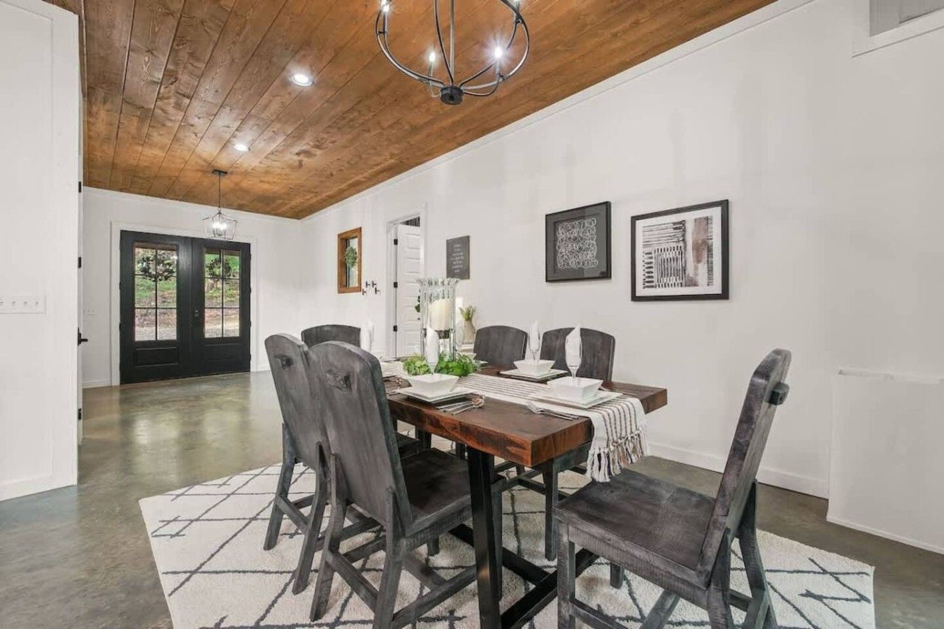 A dining area with a wooden table, chairs, and a chandelier.