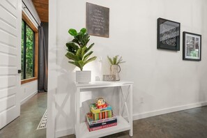 A hallway with a white console table, a potted plant, framed artwork, and a motivational quote on the wall. - Secluded Oklahoma Cabin | Hot Tub & Private Acres (Broken Bow)