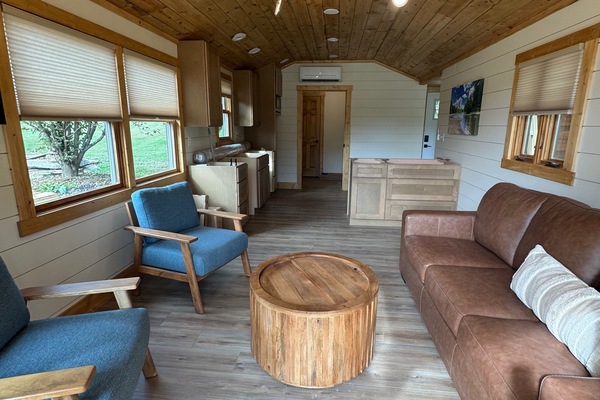 Cozy cabin living area with wood finishes, bright windows, and comfy seating
