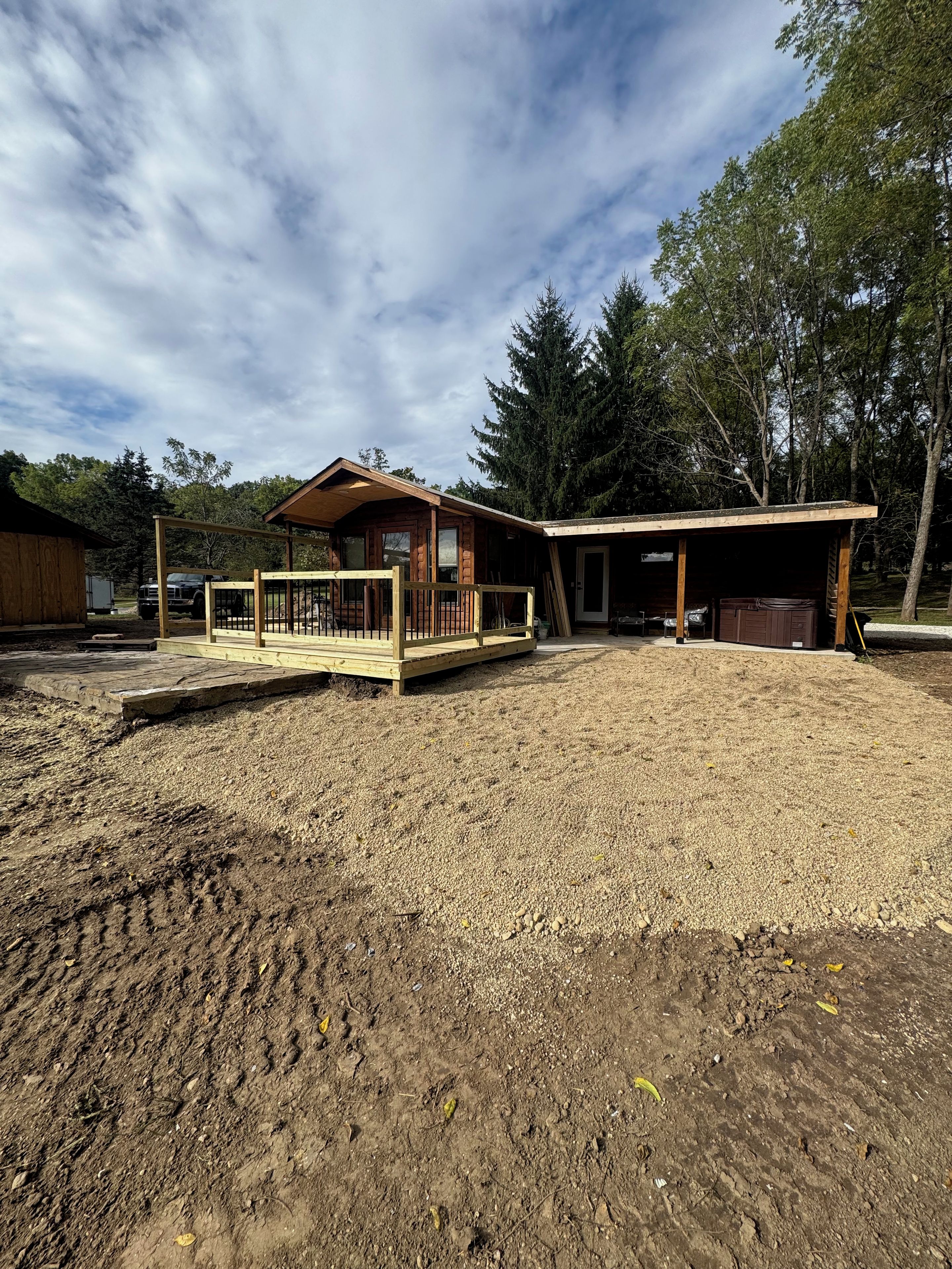 Une cabane en bois dotée d’un porche couvert et d’une zone délimitée par une clôture.