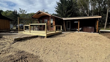 Une cabane en bois dotée d’un porche couvert et d’une zone délimitée par une clôture.