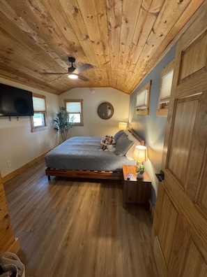 Cozy wood-accented bedroom with vaulted ceiling, TV, and warm cabin charm - The Twilight at The Narrows Cabins (Marshall)