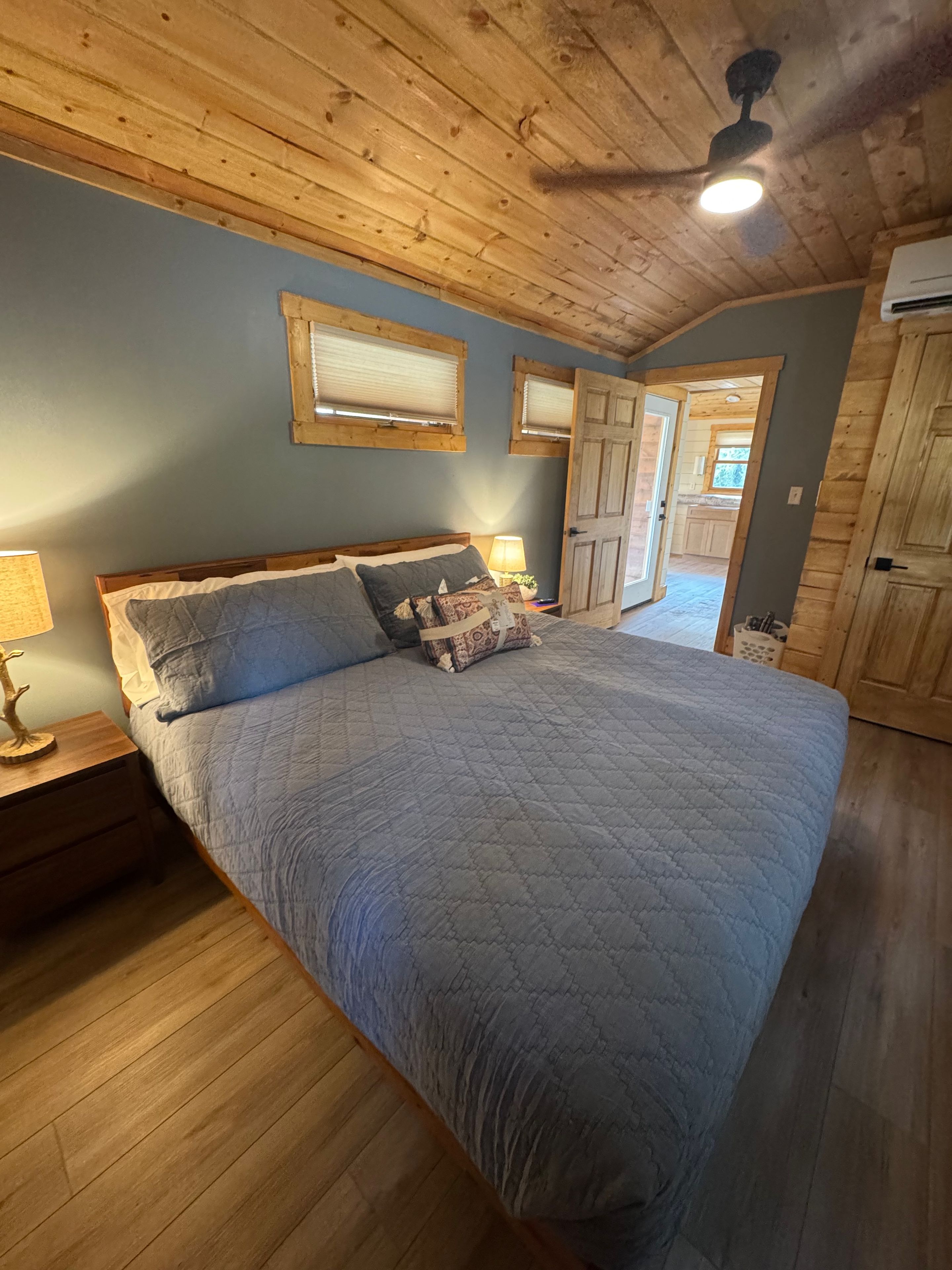Un dormitorio con una cama grande, techo de madera y una puerta que da a otra habitación.