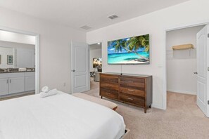 A bedroom with a bed, a dresser, a closet, and a painting of a beach scene. - Family Getaway | 6BR, Private Pool & Resort (Davenport)