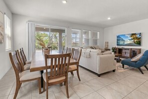 A spacious living area with a dining table, chairs, a sofa, and a television. - Family Getaway | 6BR, Private Pool & Resort (Davenport)