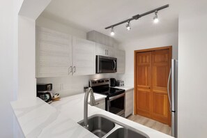Una cocina moderna con armarios blancos, electrodomésticos de acero inoxidable y una puerta de madera.