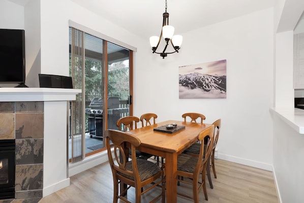 Un comedor con una mesa y sillas de madera, un candelabro y una chimenea.