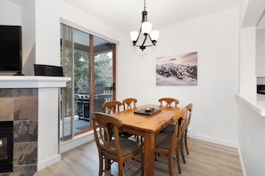 Un comedor con una mesa y sillas de madera, un candelabro y una chimenea.