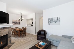 Un soggiorno moderno con camino, angolo pranzo, divano e opere d'arte alle pareti.