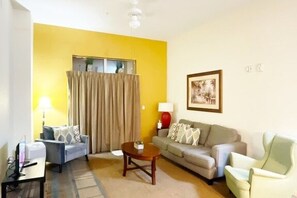Ein Wohnzimmer mit einer Couch, Sesseln, einem Couchtisch und einer Lampe.