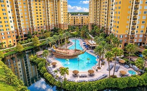 A resort with multiple high-rise buildings, a central swimming pool, and surrounding palm trees. - Buena Vista Resort Village & Spa - Top Amenities (Orlando)