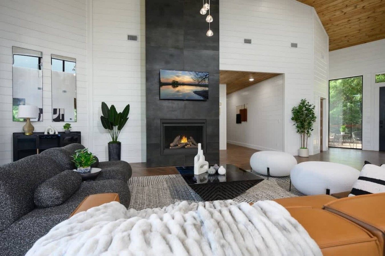 A modern living room with a fireplace, a sofa, a coffee table, and a large window.