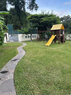 A playground with a yellow slide and a wooden climbing structure. - Amazing views, comfy and close to everything (San Marcos)