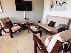 A living room with a sofa, two armchairs, a coffee table, a TV, and a painting on the wall. - Amazing views, comfy and close to everything (San Marcos)