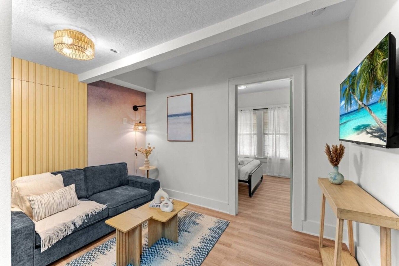 A modern living room with a sofa, coffee table, and a painting of a beach scene.