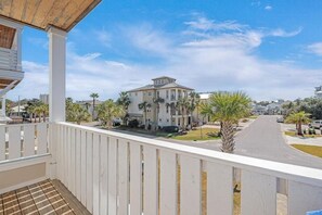 A balcony with a view of a residential street, palm trees, and a large house. - 7BR Beachside Retreat | Pool • Billiards • Miramar (Miramar Beach)