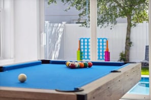 A pool table with balls, a window, and a view of a backyard with a fence and trees. - 7BR Beach Escape | Private Pool + Billiards (Miramar Beach)