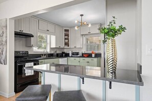 Una cocina moderna con armarios blancos, una isla central y un colgante.