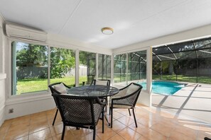 Une véranda avec une piscine, de grandes fenêtres et un sol carrelé.