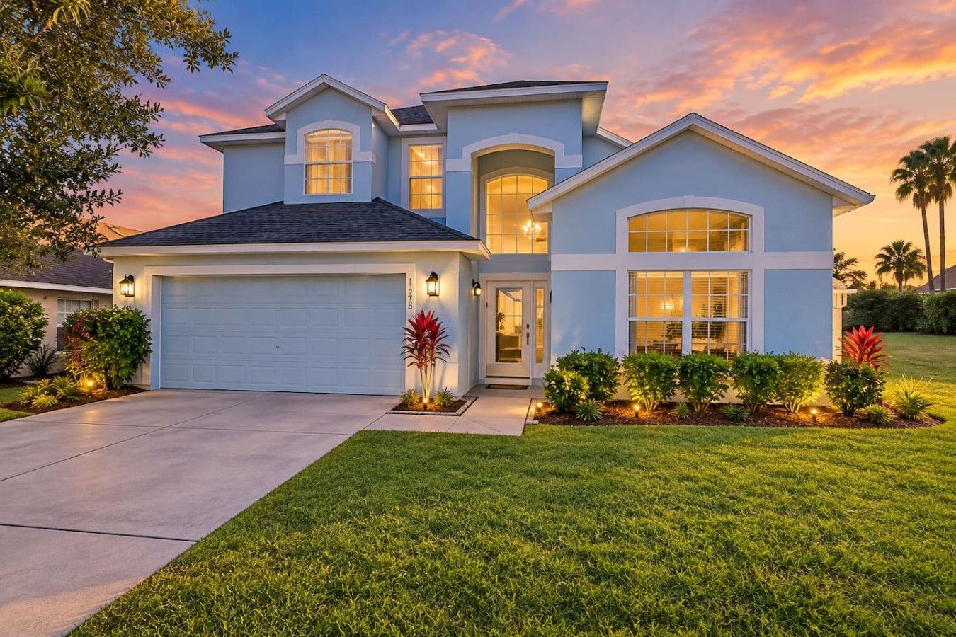 A two-story house with a garage, a covered entryway, and a well-maintained lawn.