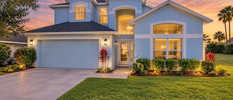A two-story house with a garage, a covered entryway, and a well-maintained lawn.