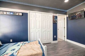 A bedroom with a bed, a wardrobe, and a door leading to another room. - Family Disney Getaway | 5BR • Pool • Near Magic (Kissimmee)