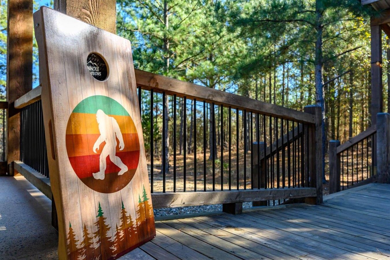 A wooden deck with a metal railing, surrounded by trees.