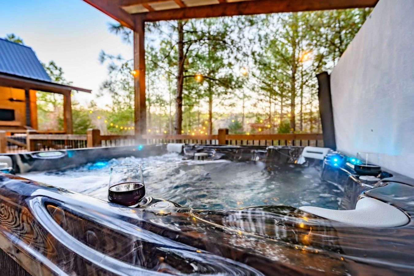 Ein Whirlpoolbereich mit Glasumrandung, umgeben von Bäumen und einer Holzterrasse.