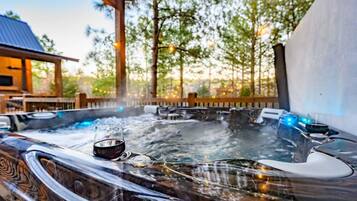Ein Whirlpoolbereich mit Glasumrandung, umgeben von Bäumen und einer Holzterrasse.