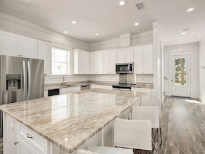 Una cocina moderna con armarios blancos, electrodomésticos de acero inoxidable y encimera de mármol.