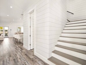 A modern interior with a staircase, a dining area, and a kitchen. - 7BR Miramar Getaway | Spacious & Near the Beach (Miramar Beach)