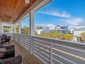 A covered outdoor area with a railing, wicker furniture, and a view of neighboring houses. - 7BR Miramar Getaway | Spacious & Near the Beach (Miramar Beach)