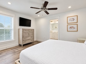 A bedroom with a bed, a ceiling fan, a dresser, a TV, and framed pictures on the wall. - 7BR Miramar Getaway | Spacious & Near the Beach (Miramar Beach)