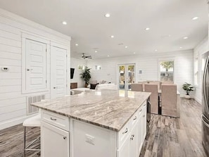 A spacious kitchen with a marble countertop, white cabinetry, and a dining area with chairs. - 7BR Miramar Getaway | Spacious & Near the Beach (Miramar Beach)