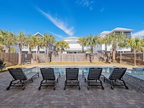 A swimming pool with lounge chairs, surrounded by palm trees and a wooden fence. - 7BR Miramar Getaway | Spacious & Near the Beach (Miramar Beach)