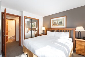 Habitación de hotel con una cama grande, dos mesitas de noche con lámparas, un cabecero de madera, un espejo y un cuadro en la pared.