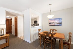 Un comedor con una mesa y sillas de madera, una lámpara colgante y un cuadro en la pared.