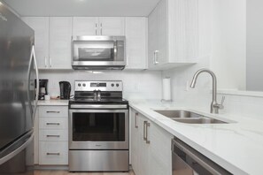 Una cucina moderna con elettrodomestici in acciaio inossidabile, mobili bianchi e un lavello a due vasche.