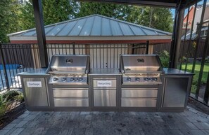 A stainless steel barbecue grill set with labeled compartments for garbage and recycling, situated on a wooden deck. - Lake Placid Lodge | 2 Bedroom | Pool access (Whistler)