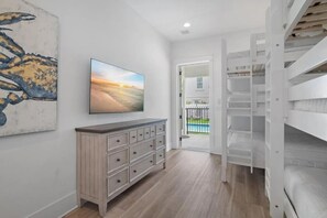 Een slaapkamer met een stapelbed, een houten dressoir, een schilderij en uitzicht op een zwembad.
