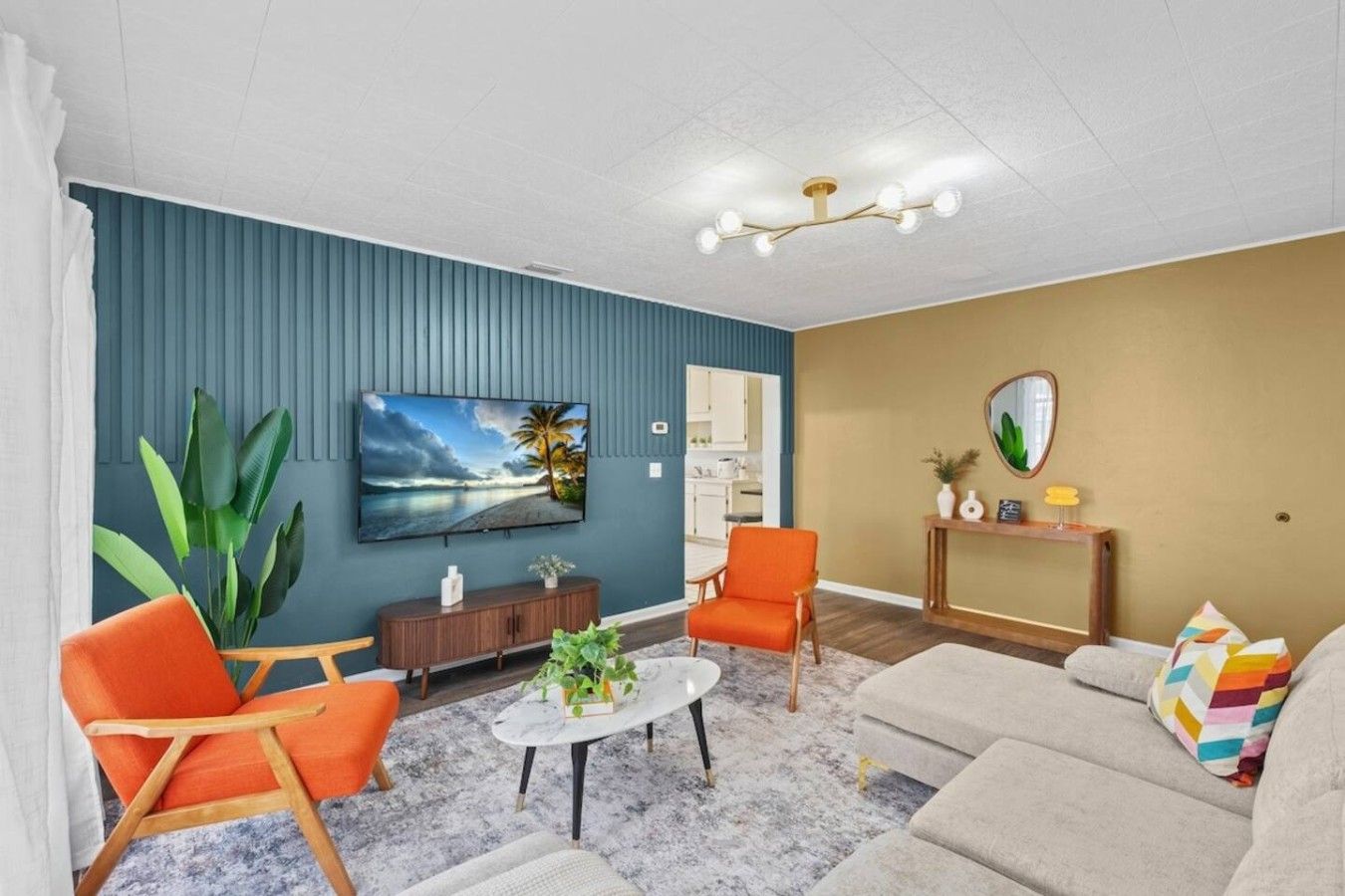 A living room with a television, a sofa, two armchairs, a coffee table, and a console table with decorative items.