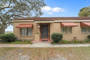 A two-story building with a brown facade, a tiled roof, and awnings over the windows. - Boho Lakeside Retreat | Walk to Lake Toho (Kissimmee)
