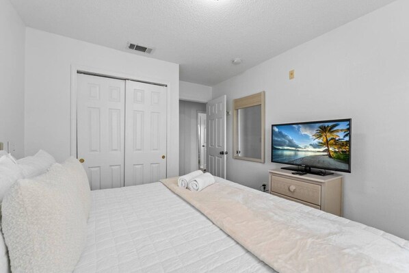 A bedroom with a bed, a television, a dresser, and a door. - Lake Berkley Retreat | Pool • Fishing • Clubhouse (Kissimmee)