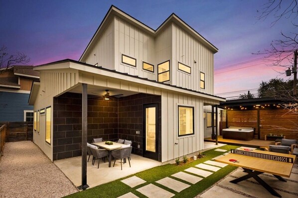 Uma casa moderna de dois andares com varanda coberta, área de refeições e hidromassagem.