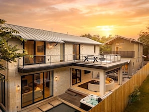 Une maison moderne à deux étages, dotée d’un balcon, de grandes fenêtres et d’un jacuzzi.